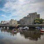 white and red boat on water near gray concrete building during daytime