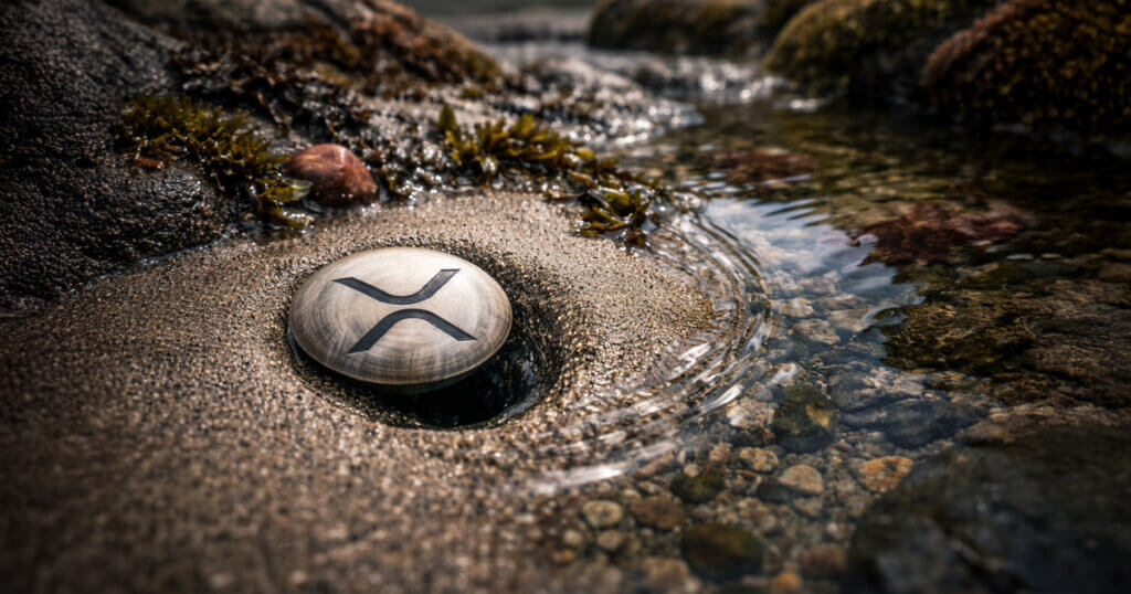 XRP token lodged in sand beside flowing water, symbolizing how XRPL avoided a vulnerability that could have drained user funds