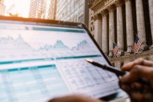Analyst reviewing market data on a laptop outside a Wall Street building, reflecting a $10 trillion opportunity as Washington updates 401(k) rules