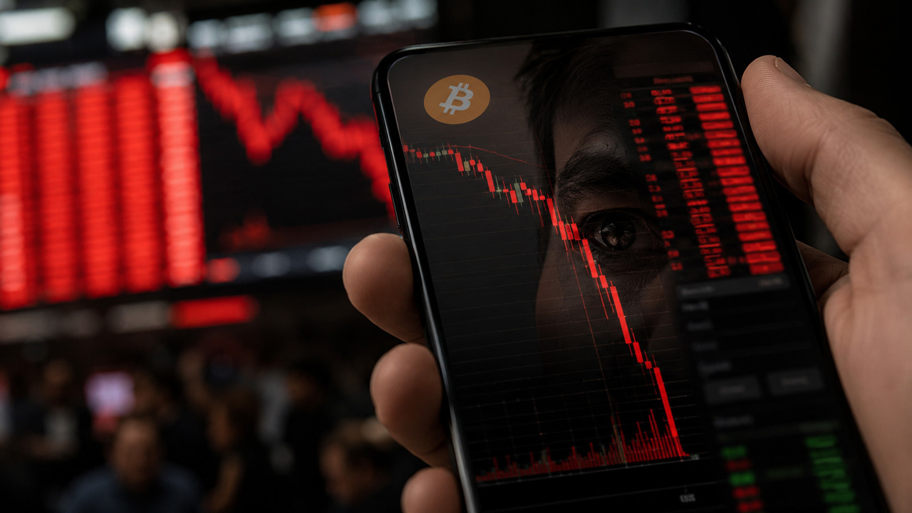 Close-up of a smartphone displaying a falling Bitcoin price chart, overlaid on a red market backdrop with a Bitcoin symbol and blurred cryptocurrency-themed imagery, illustrating a Bitcoin market downturn and price volatility.