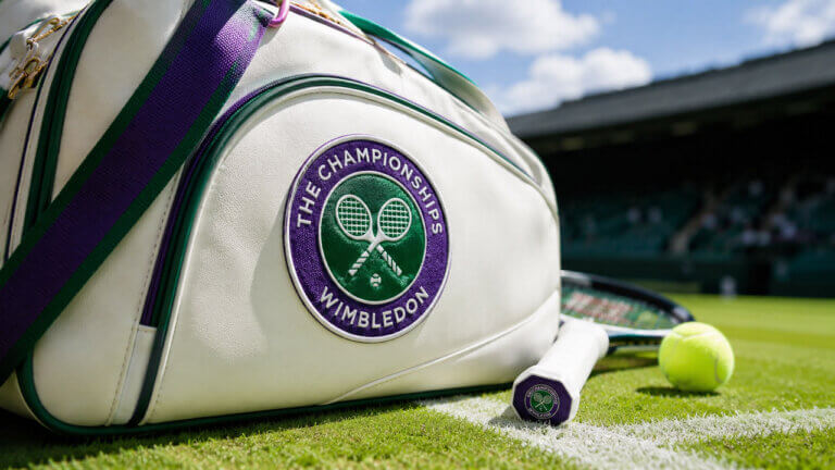 Wimbledon-branded tennis bag with racket and ball on grass court under bright daylight.