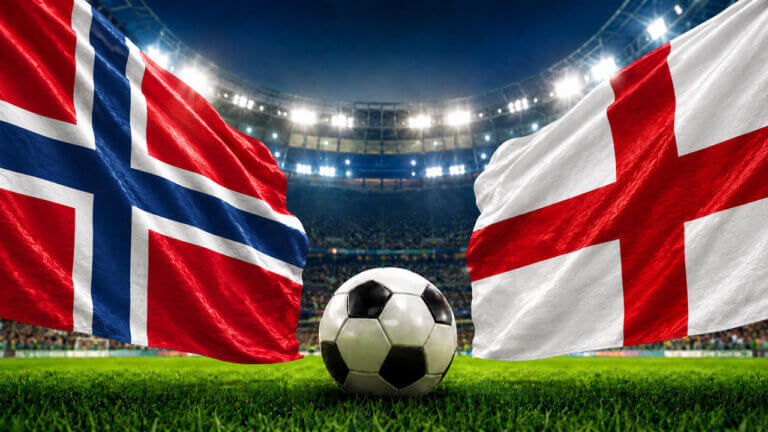 Norway and England flags facing each other with a soccer ball at midfield inside a brightly lit football stadium