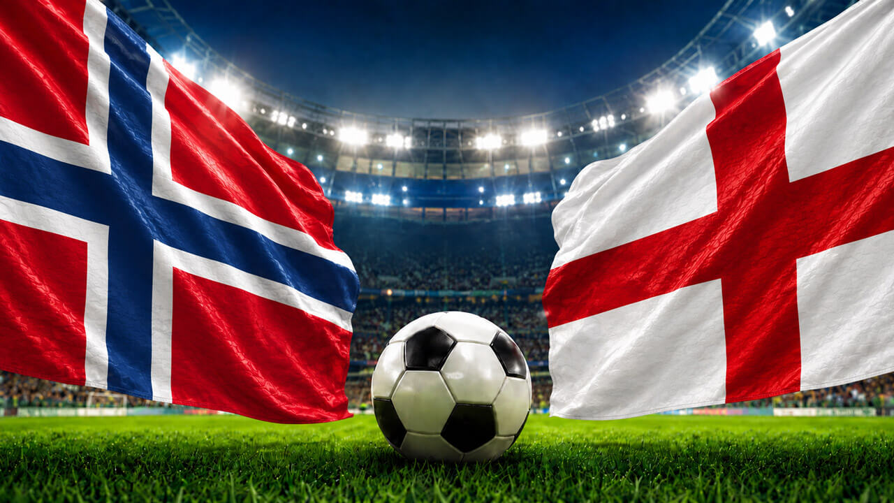 Norway and England flags facing each other with a soccer ball at midfield inside a brightly lit football stadium