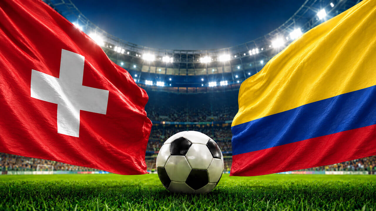 Switzerland and Colombia flags facing each other with a soccer ball at midfield inside a brightly lit football stadium